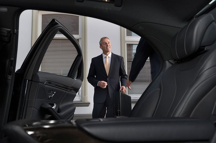 Business passenger entering a chauffeured executive sedan