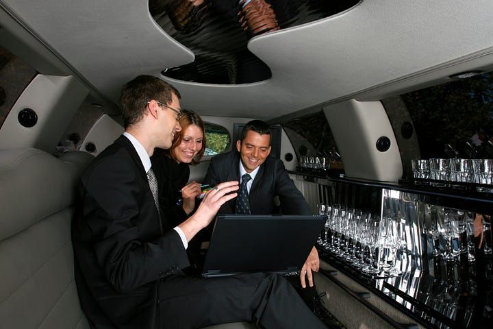 Business passengers using a laptop inside a stretch limousine