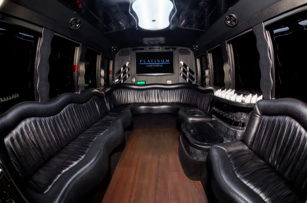 Limo party bus interior with black leather seating and wood flooring