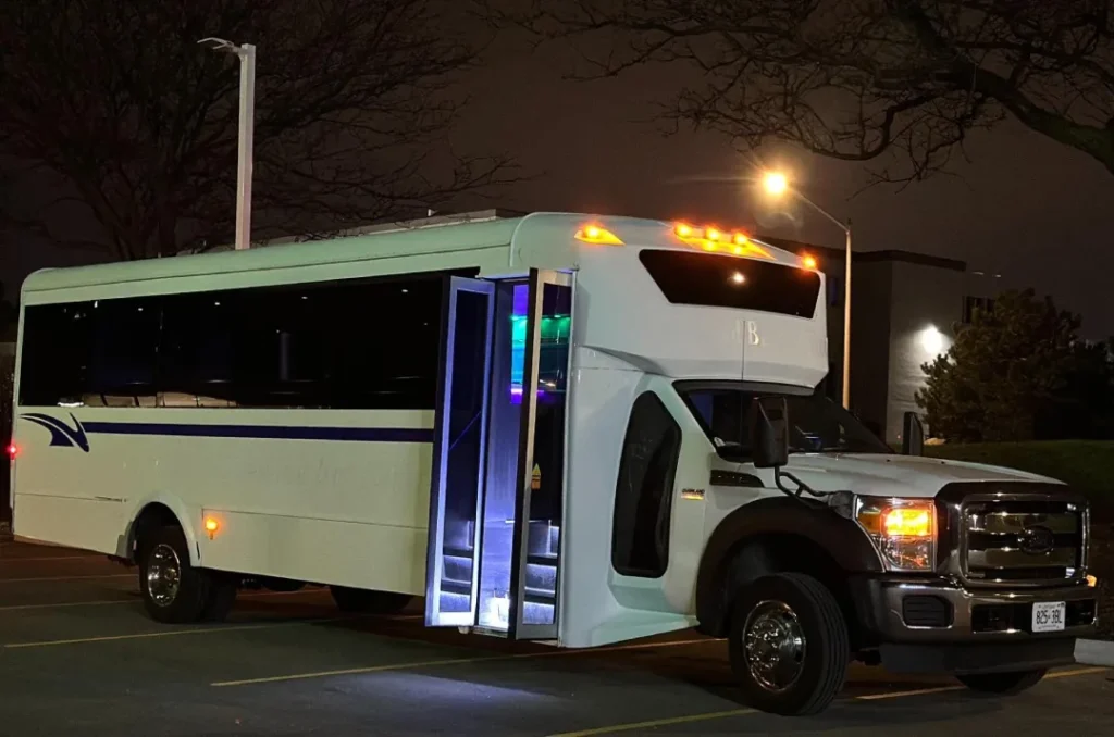 White limo party bus with illuminated entrance at night